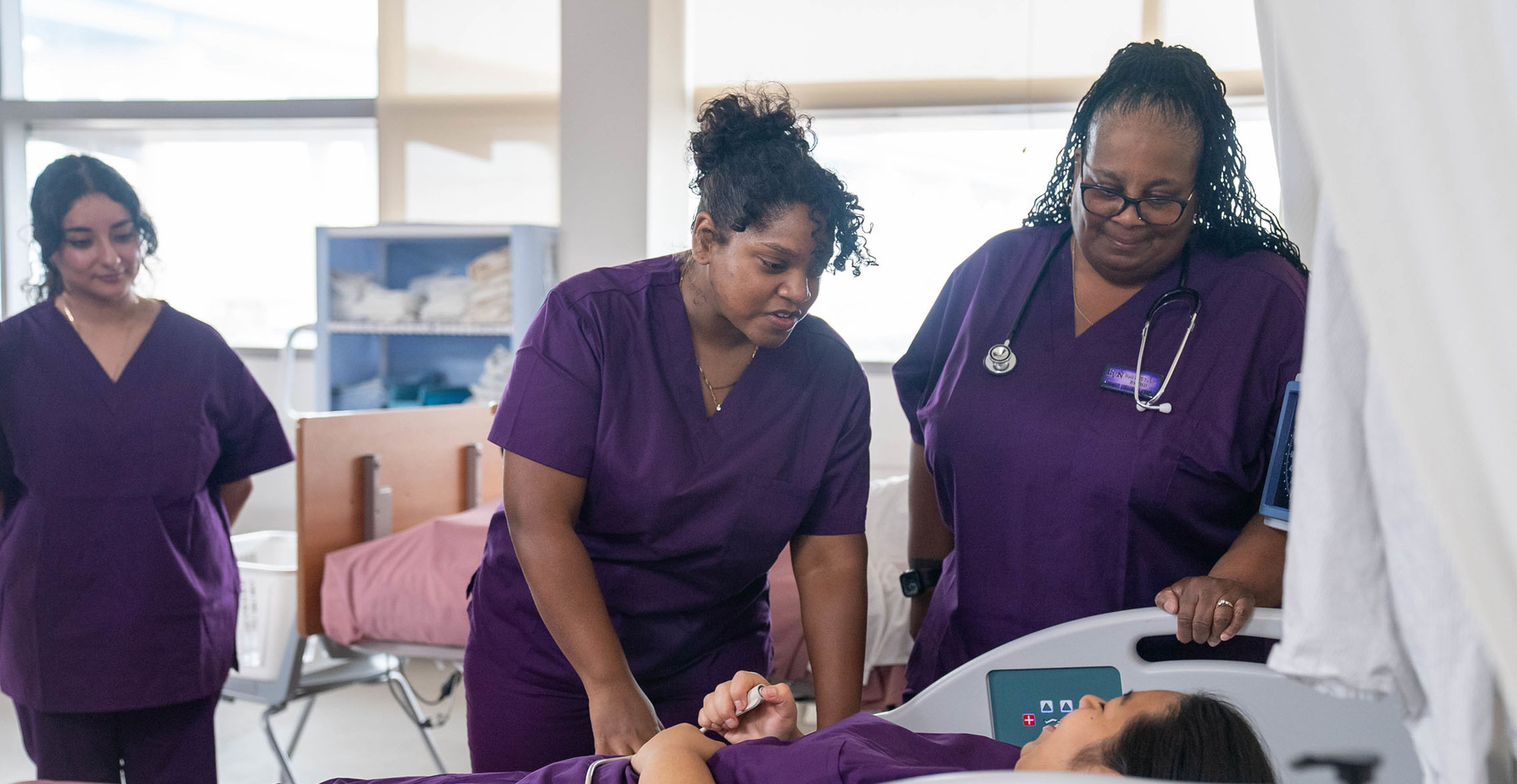 Healthcare students standing by a hospital bed